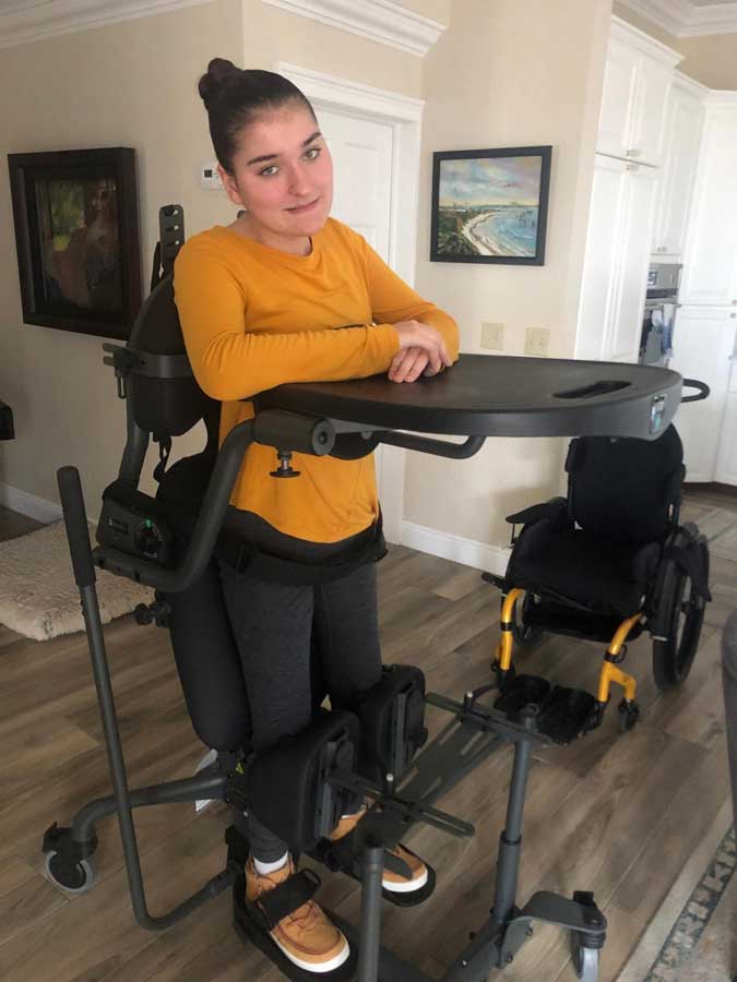 Woman standing with assistive standing device.
